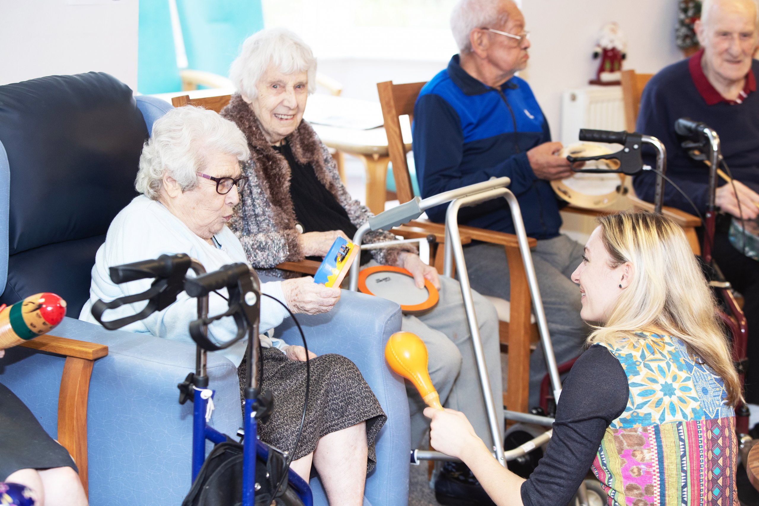 Three people with dementia being taught to play musical instuments by a Music in Mind therapist.