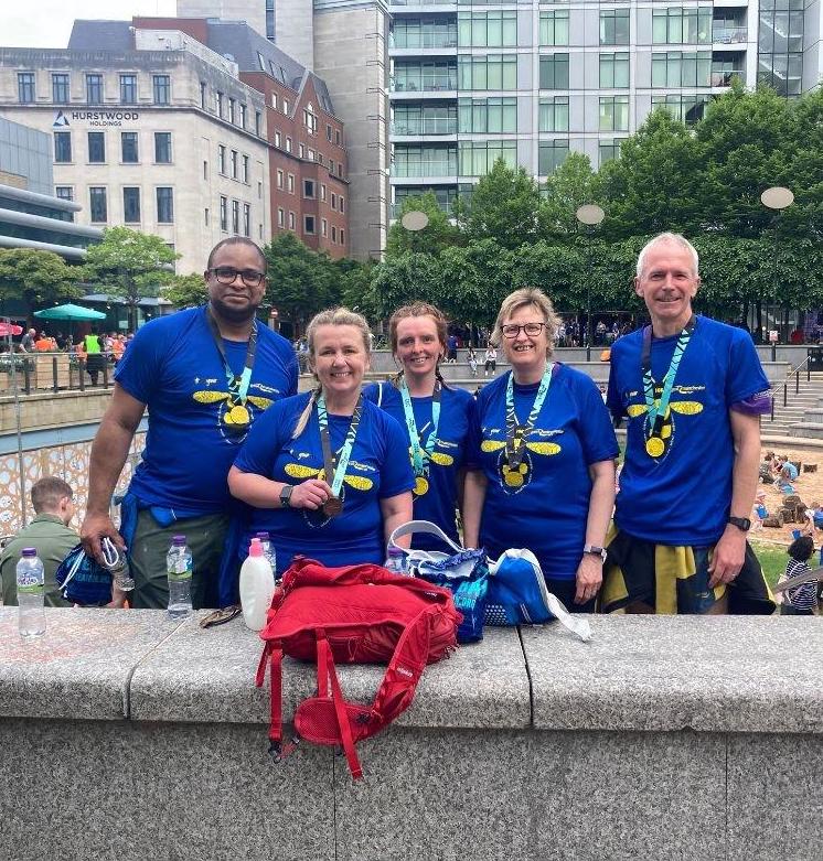 5 happy runners with their medals smile at the camera