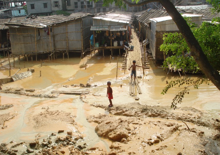 Image of children playing in a poor neighborhood amidst mud and water