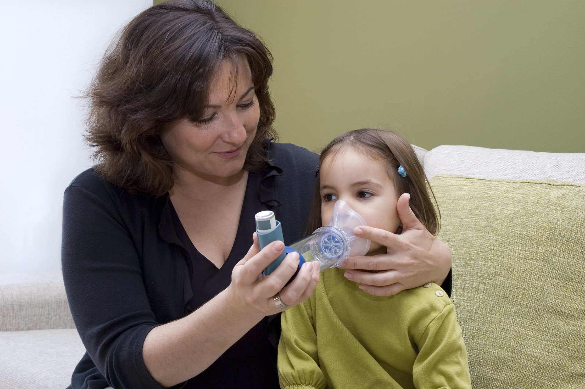 A mother helping her daughter use an inhaler