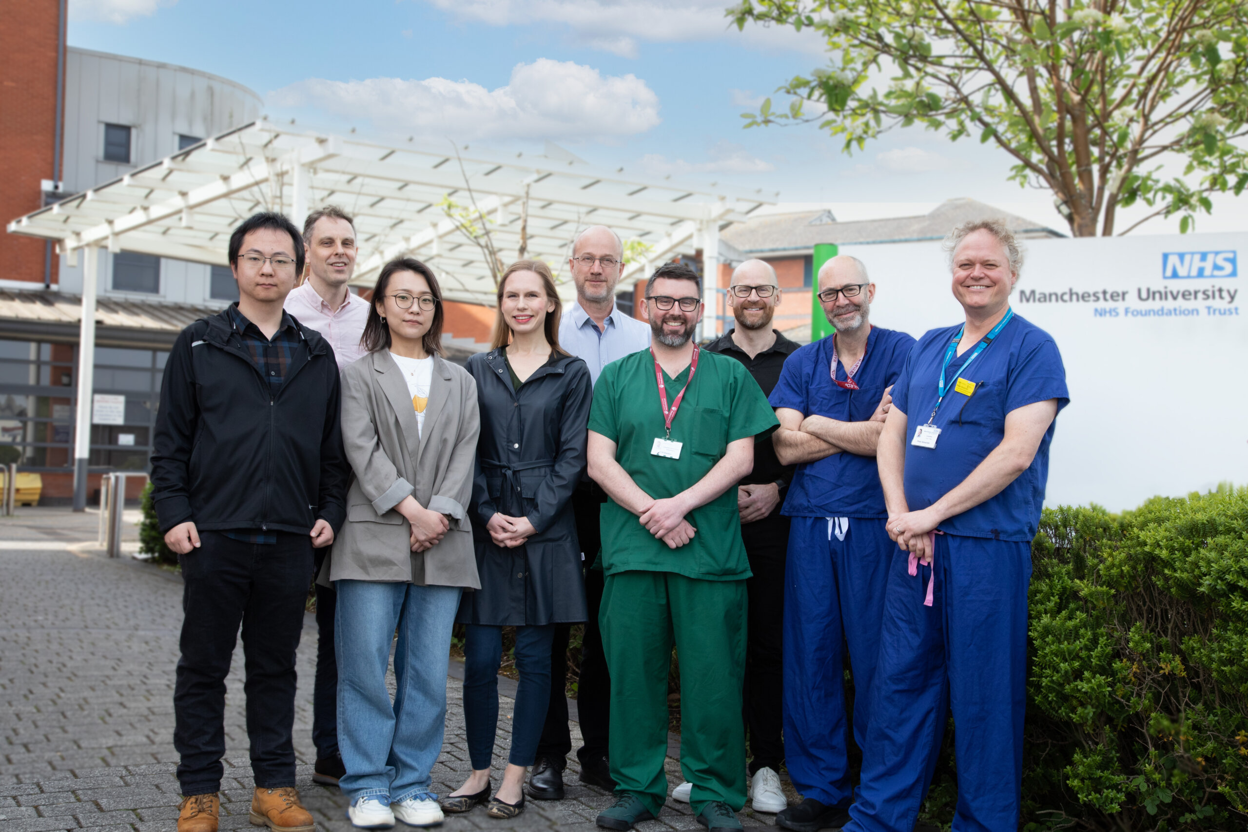 Group of medical professionals and engineers stand in a group outside a hospital : the GiFT team)