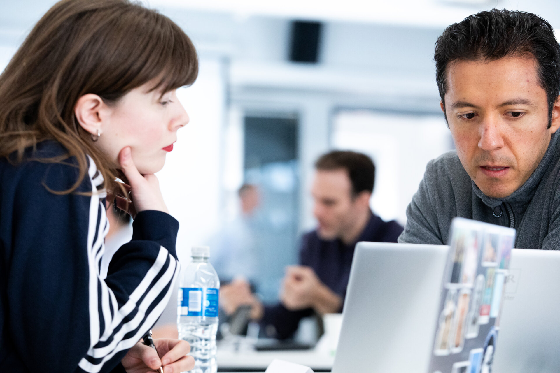 two people sit talking at a round eirh a laptop