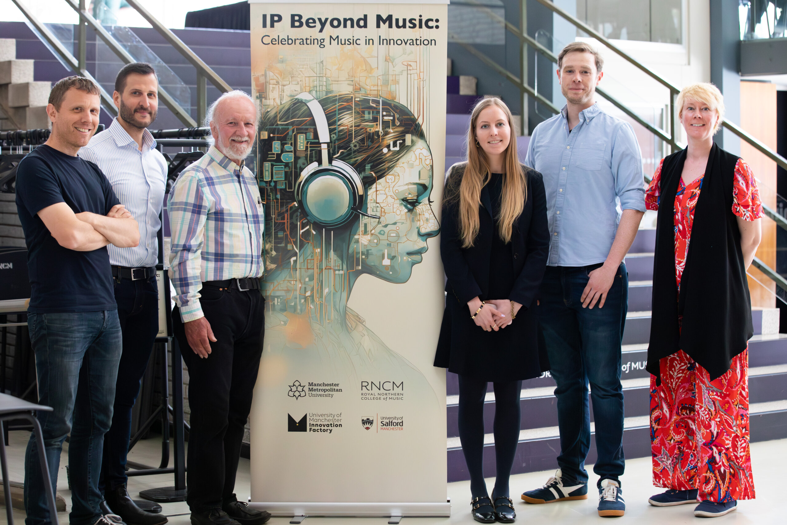 6 people stand smiling at the camera in front of an event banner for 'IP Beyond Music'. The banner illustration shows a woman wearing headphones.