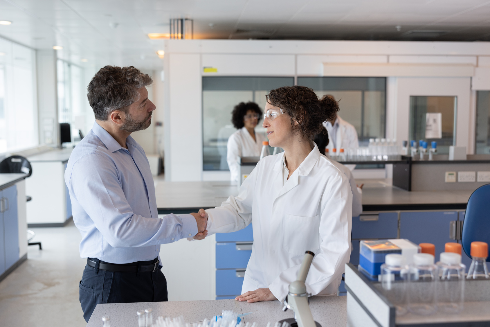 Scientist shaking hands with businessman in pharmaceutical laboratory