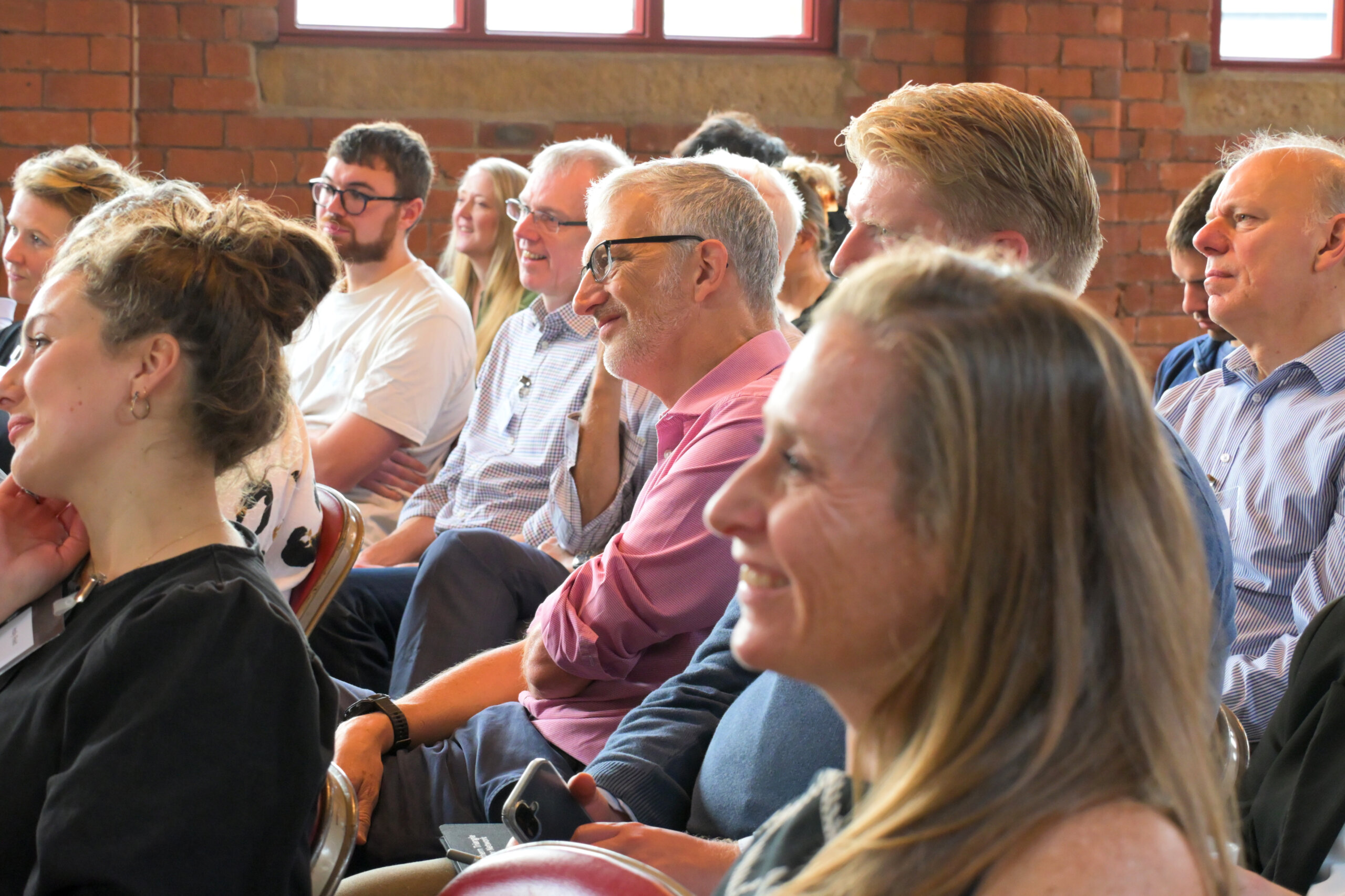 people sit in an audience smiling at the person talking (not shown)